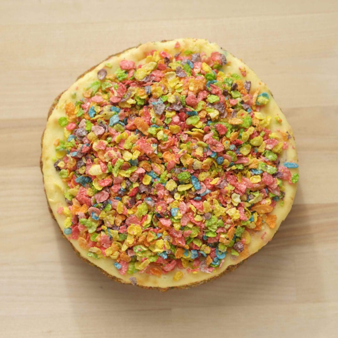 Colorful cereal-topped dessert on wooden surface.