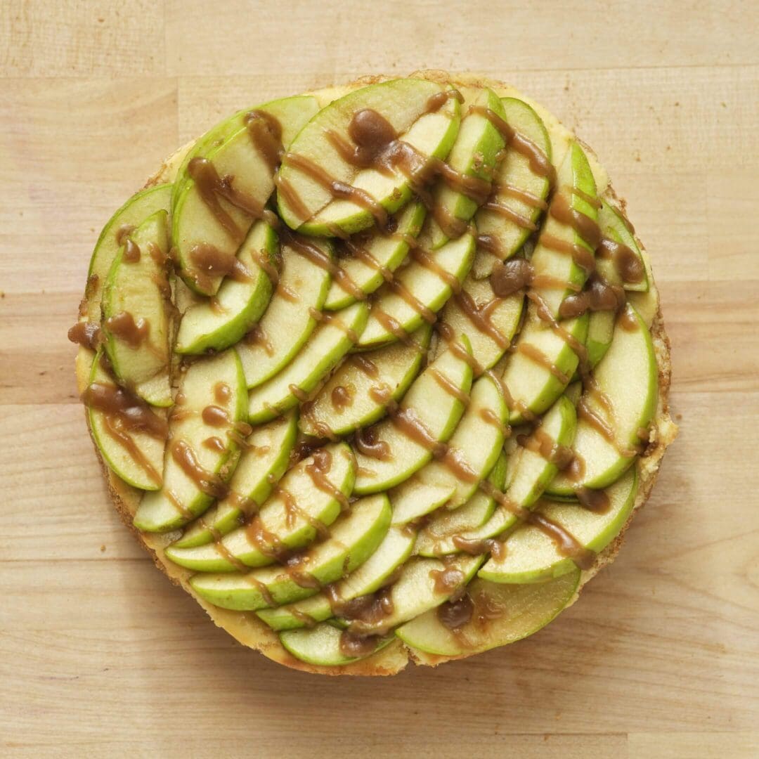 Apple tart with caramel drizzle on wood.