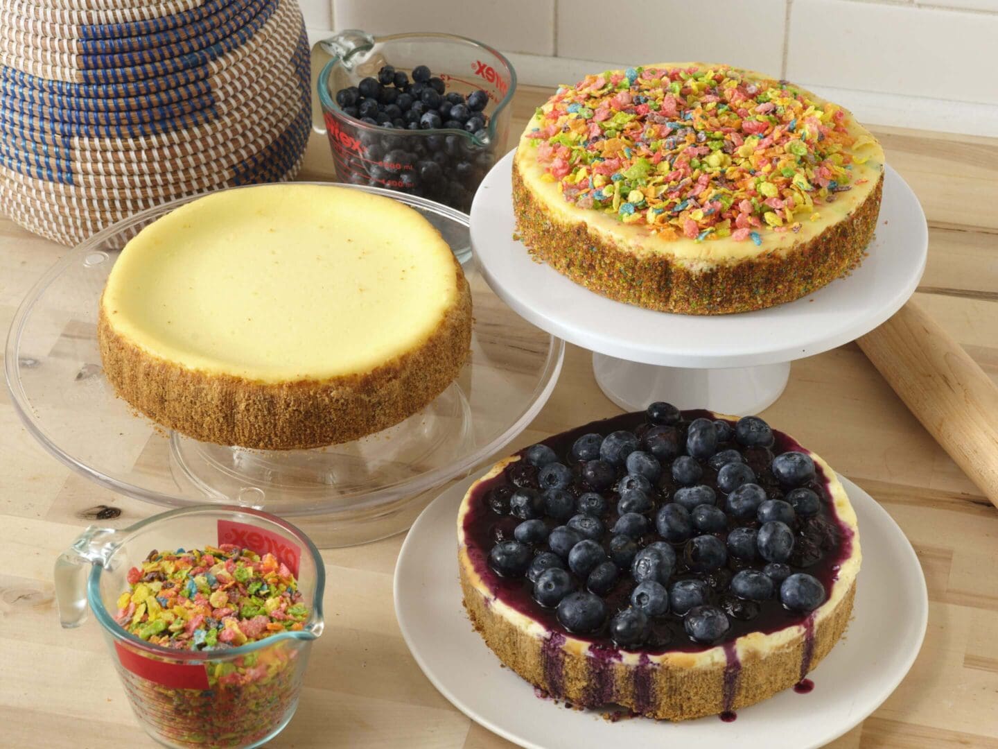 Three cheesecakes with colorful toppings displayed.