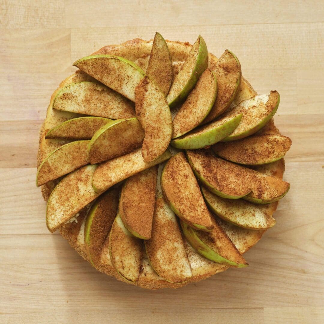 Apple pie with cinnamon on wooden surface.