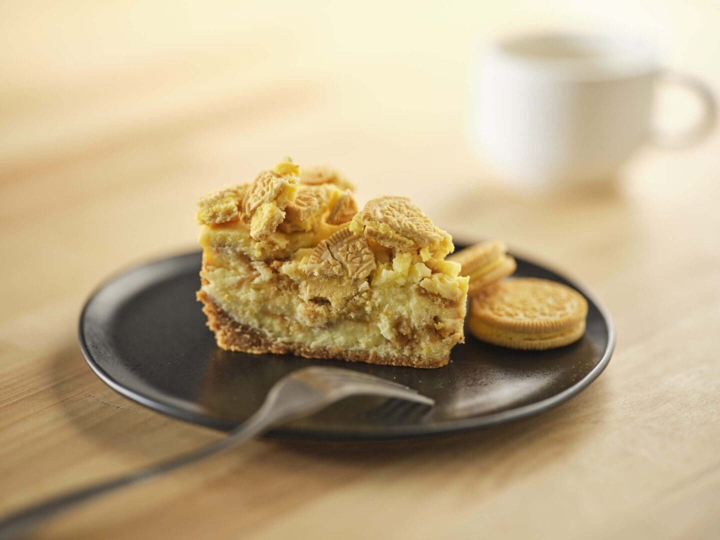Cake slice with cookies on black plate.