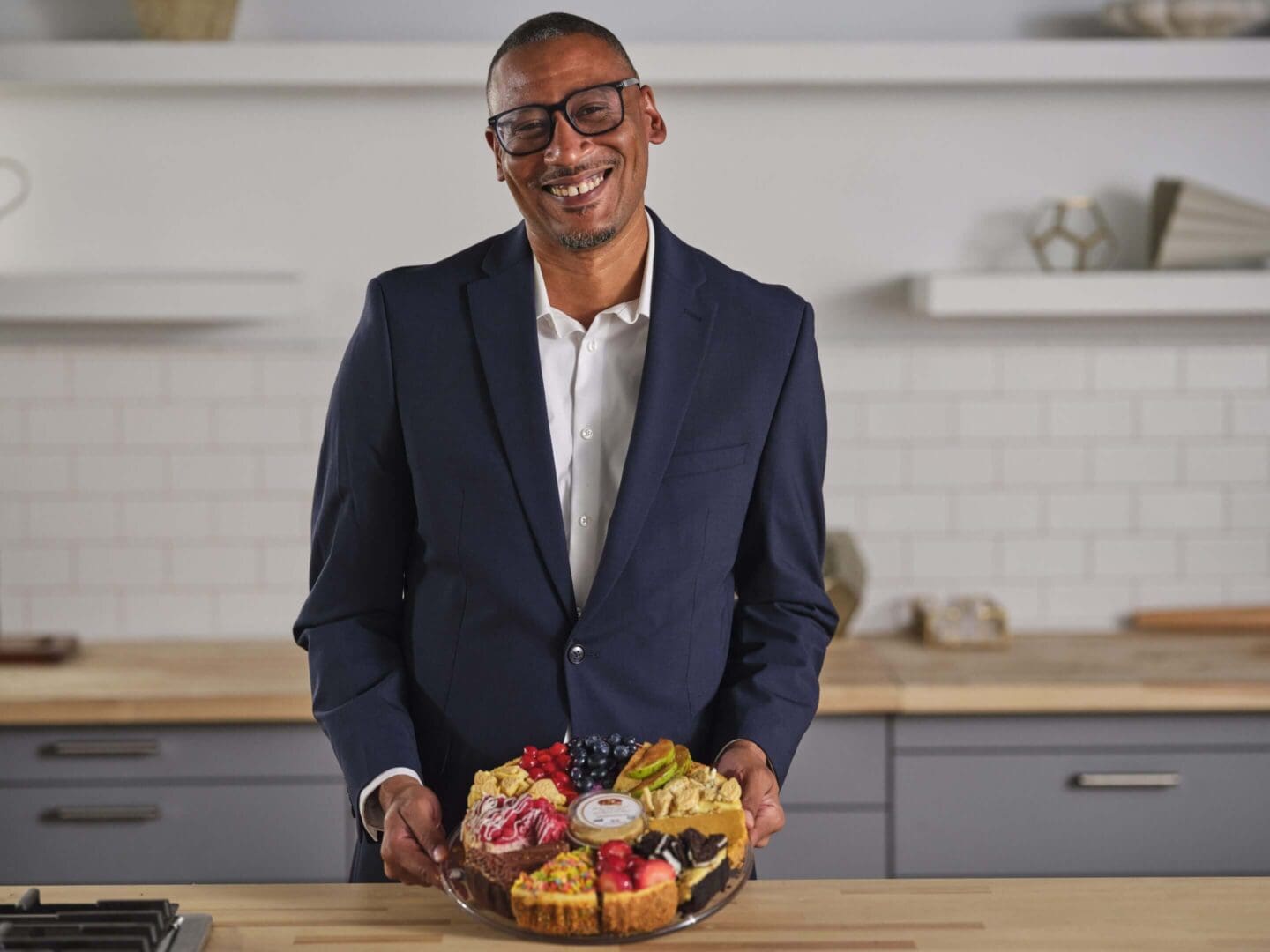 Man smiling while holding a dessert platter.