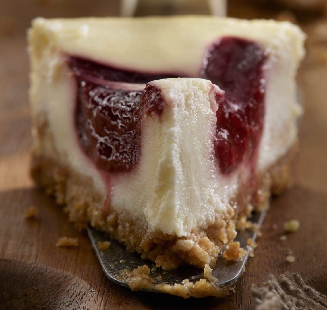 Cheesecake slice with berry filling on spatula.
